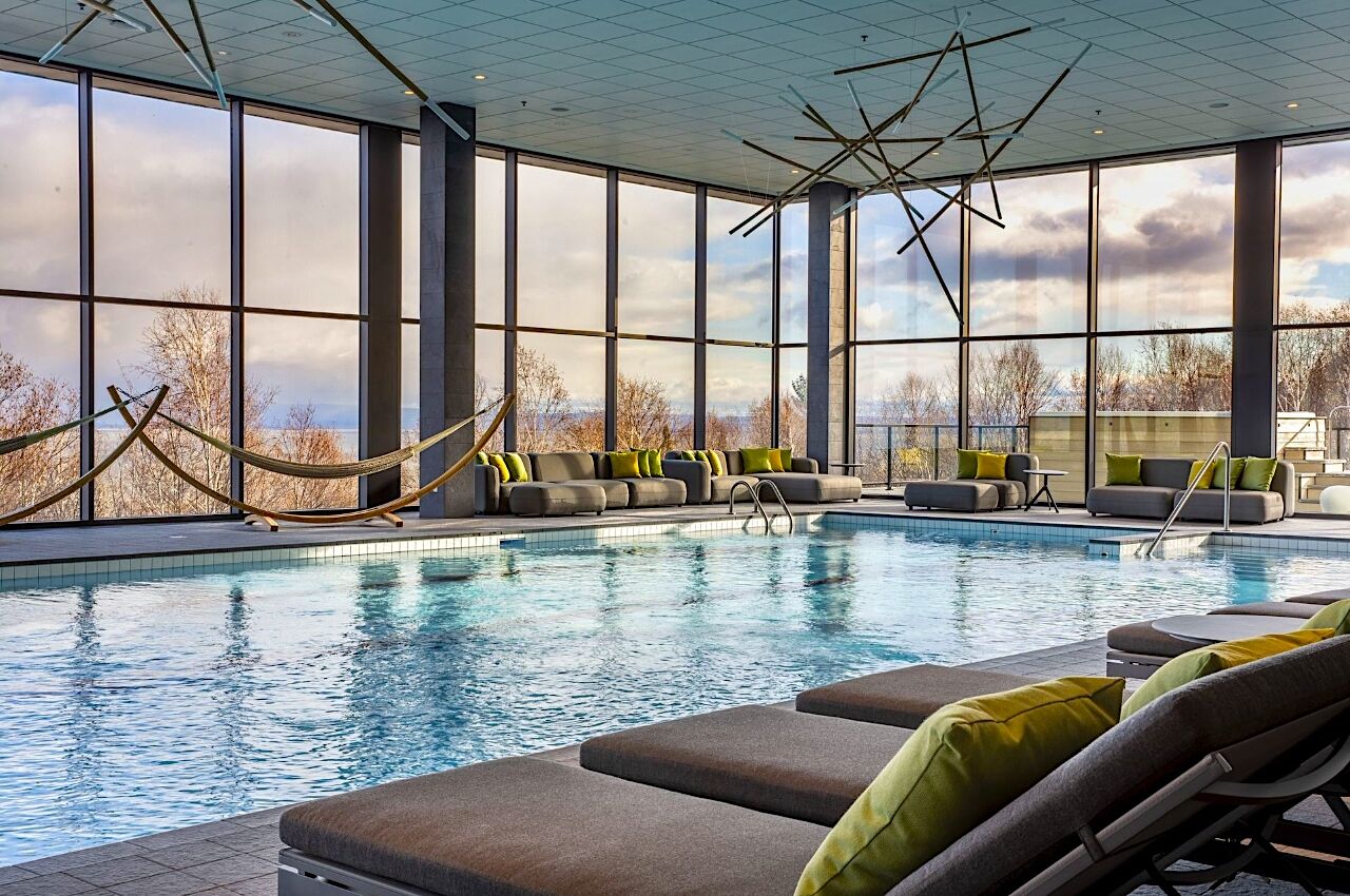 Indoor hotel pool at Club Med in Qubec with sitting area, lounge chairs and hammocks 