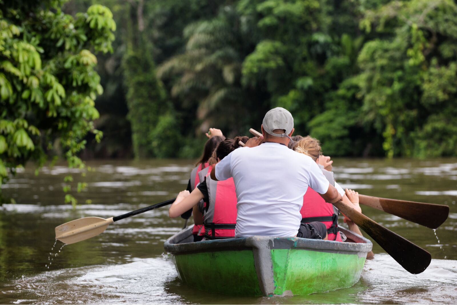 People exploring a wild nature area by rowing boat. Ecotourism concept. Tortuguero national park. Limon, Costa Rica.