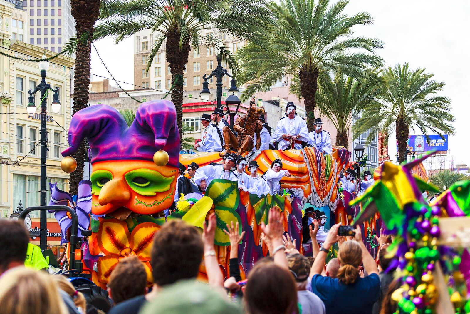 New Orleans' Mardi Gras parades with people dressed up and floats handing out goods and beads