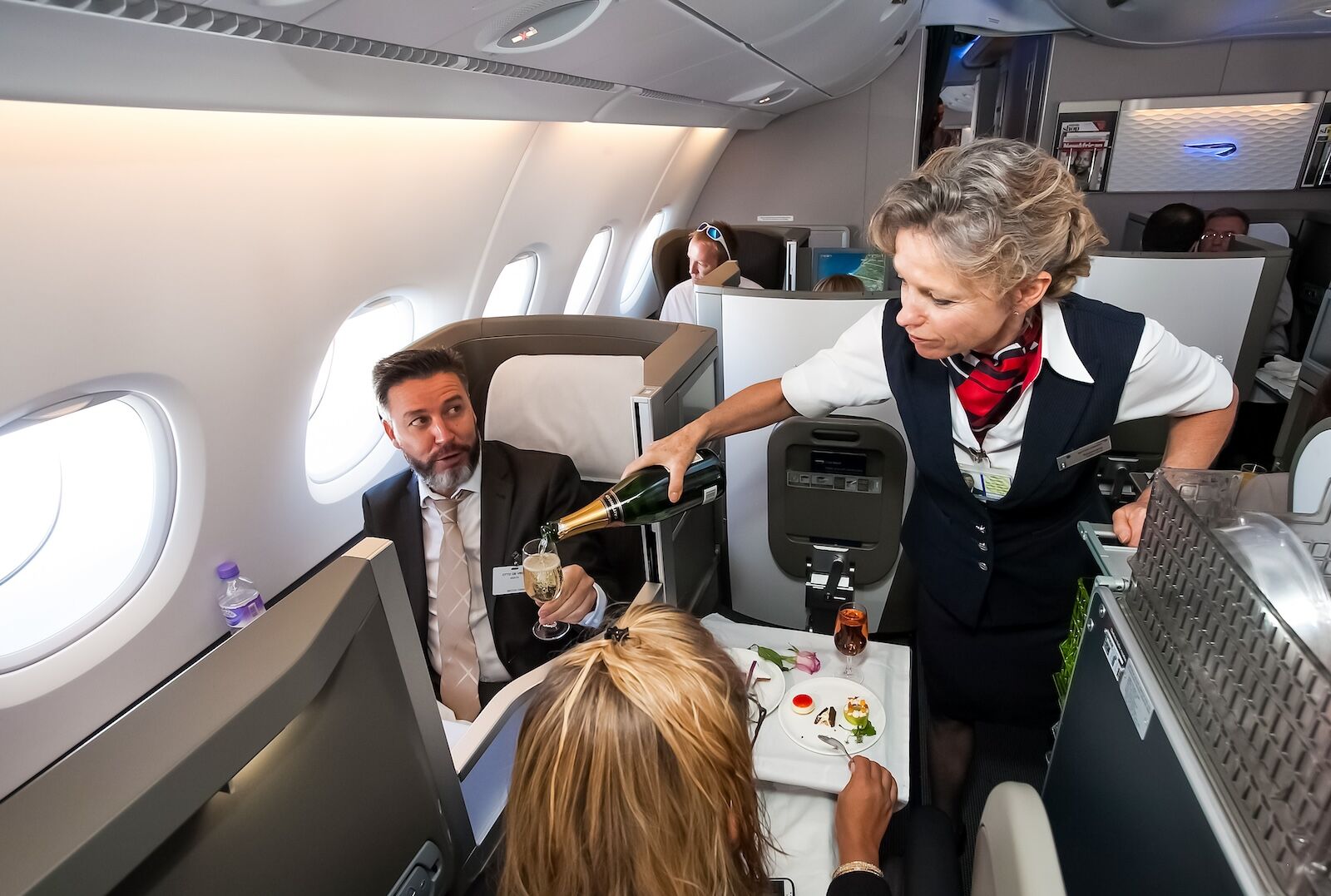 flight attendant pouring champagne in british airways business class