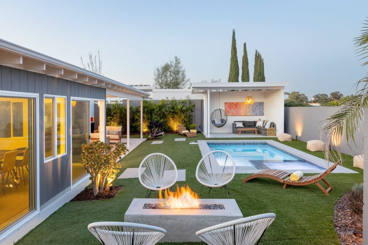 backyard area with pool and multiple seating areas and fire pit of newly built mid century home airbnb san diego