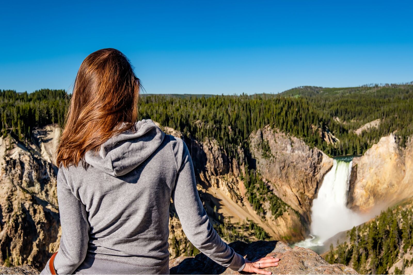 Woman tourist overlooking Lower Falls waterfall in the Grand Canyon of Yellowstone National Park, Wyoming, USA, where to travel