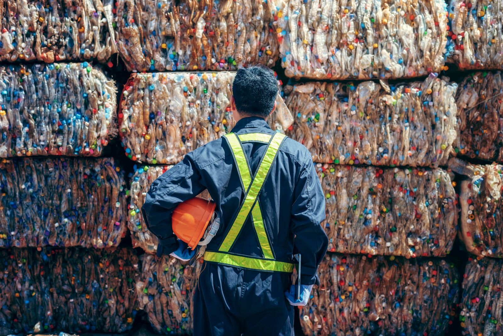 a factory working looking at a wall of recycled plastics 
