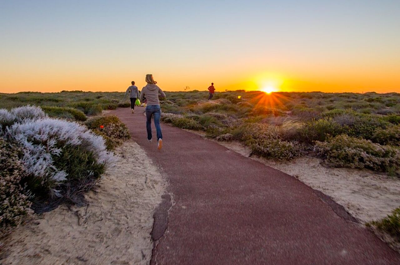 People walk up path towards sunset in Perth Australia 