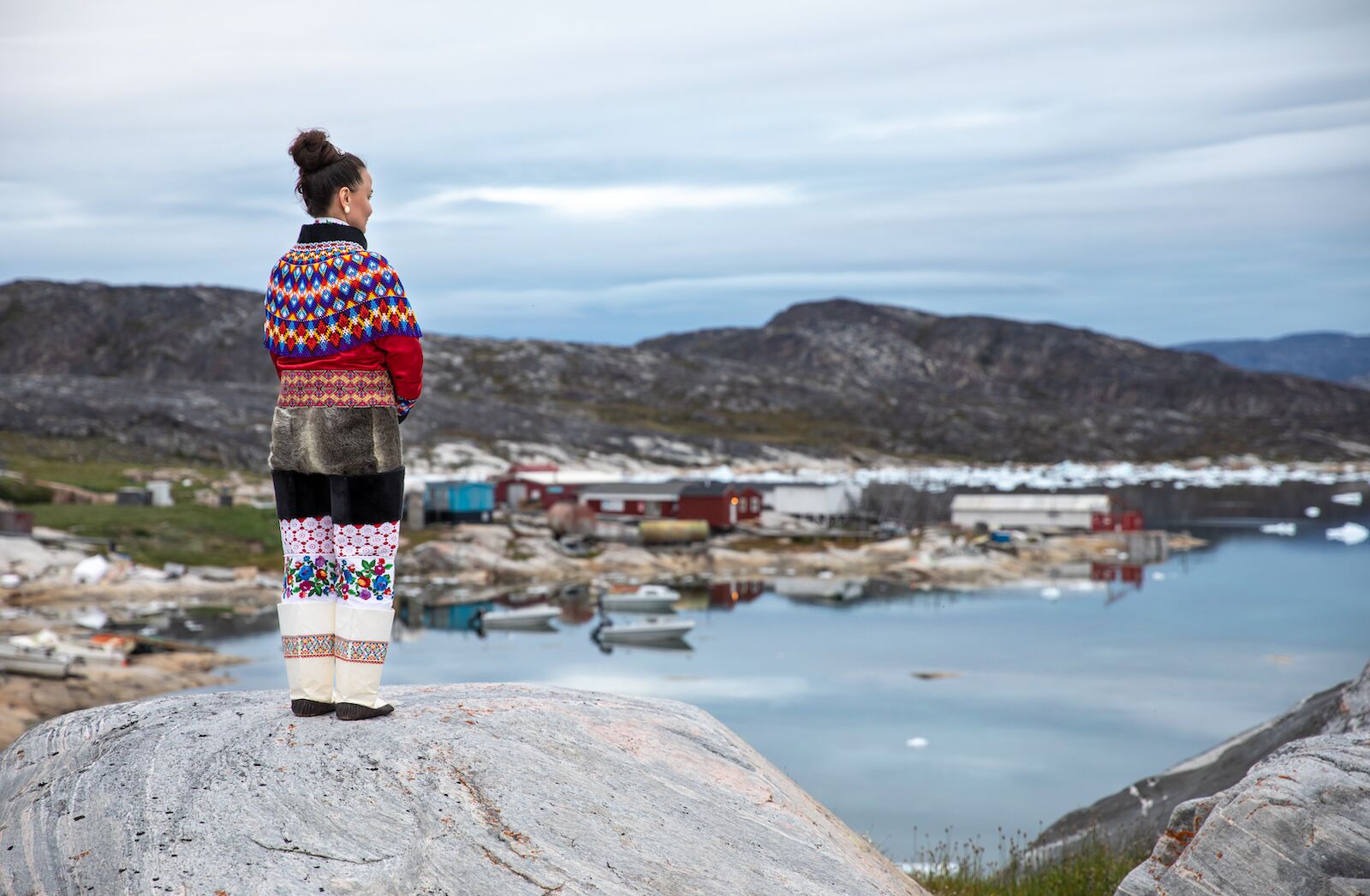 Woman wearing the national dress of Greenland looking out at the landscape.