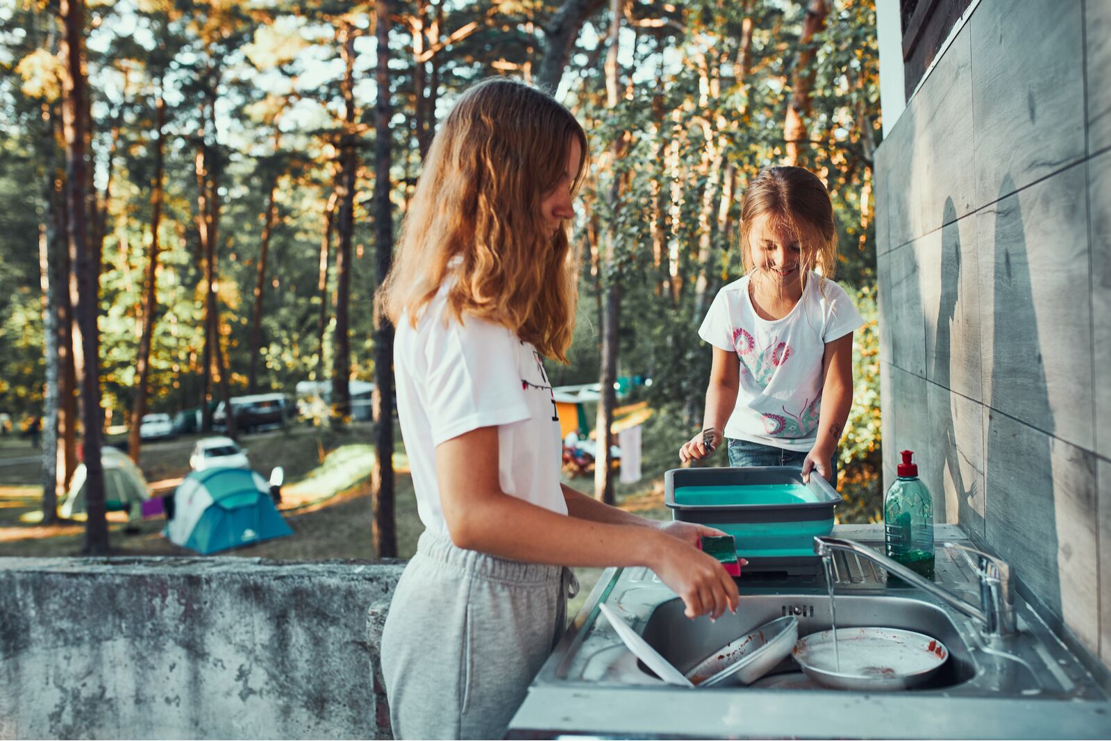 Young girls washing dishes at camp