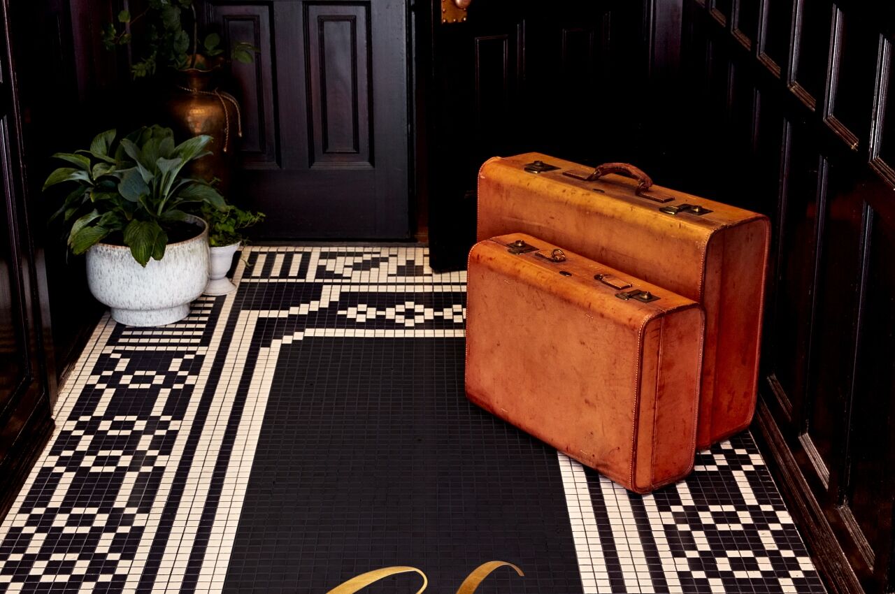 Two brown leather suitcases on tile floor at The Guild House Hotel