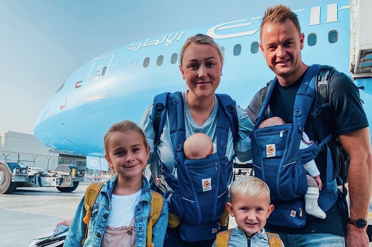 Family of six in front of blue plane