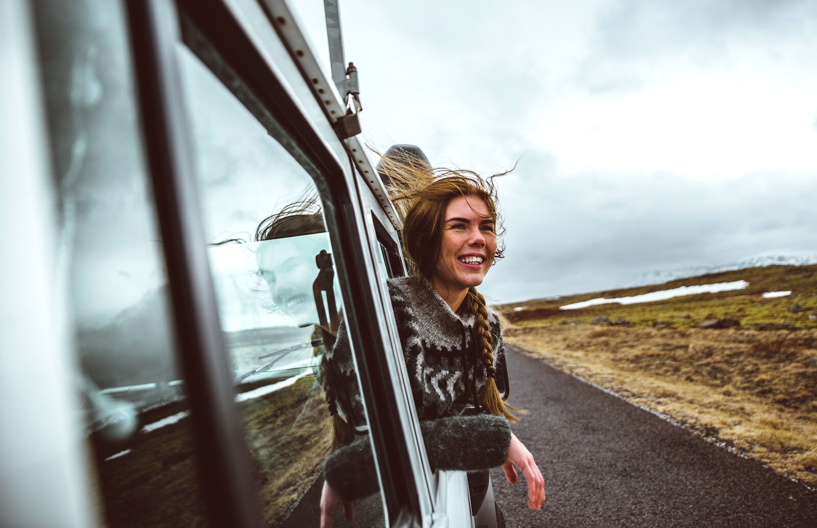 person leaning out of a car window during a trip to Iceland. Learning out Iceland's language is valuable to travelers to Iceland.