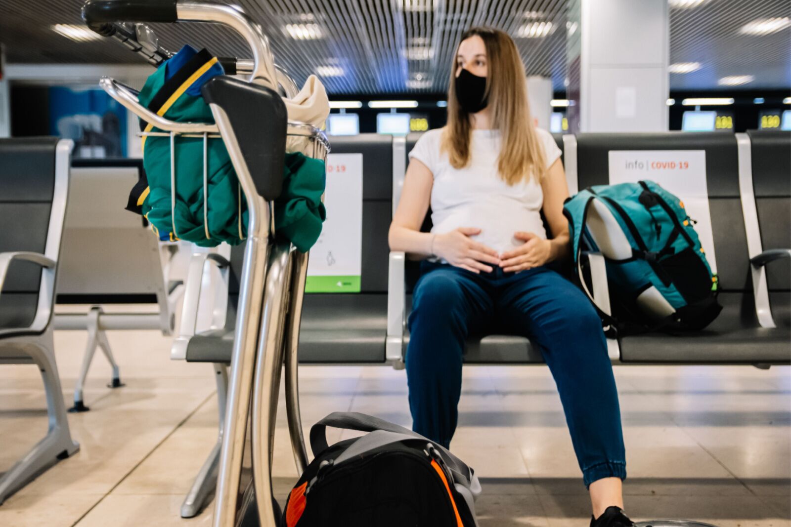 Pregnant woman sitting down in airport terminal