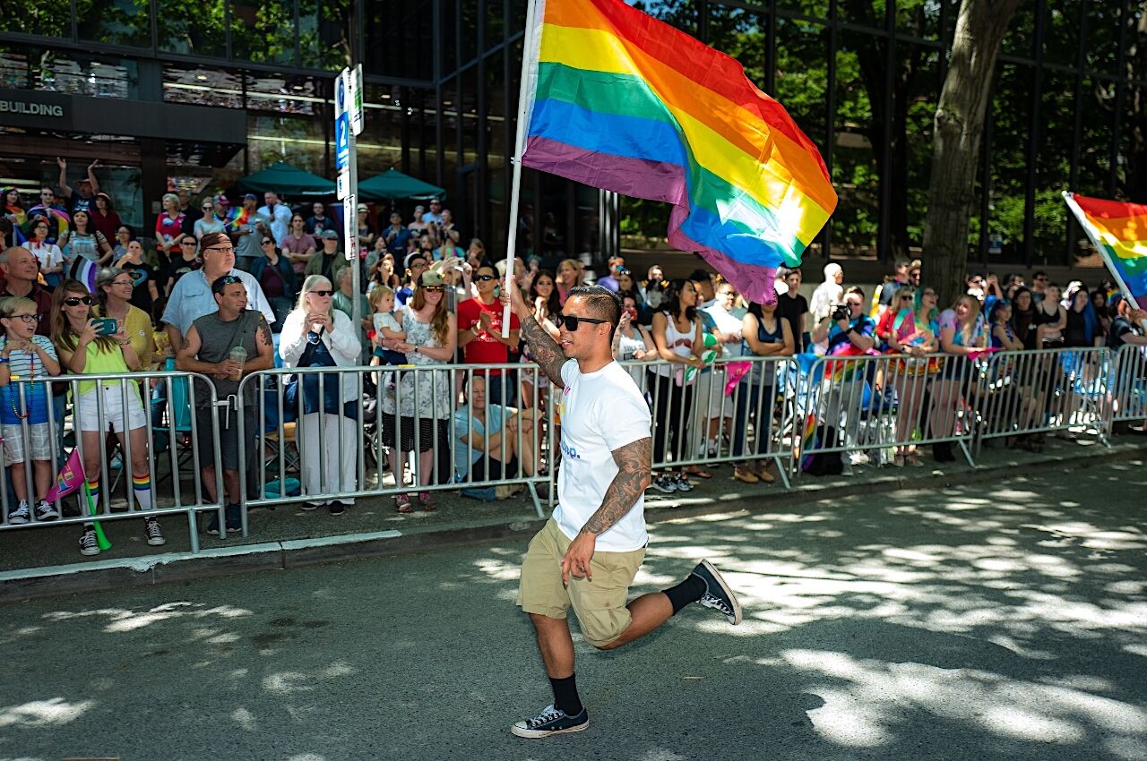 Man runs with Pride flag at Seattle Pride month 2022