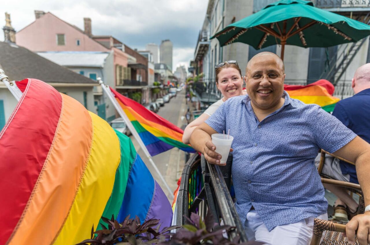 People on balcony with rainbow flag at New Orleans Pride 