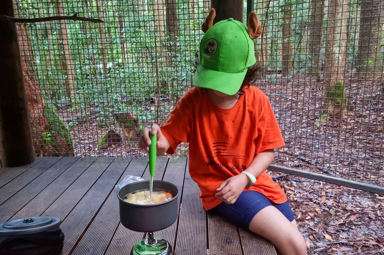 Young boy cooking on overnight backpacking with kids
