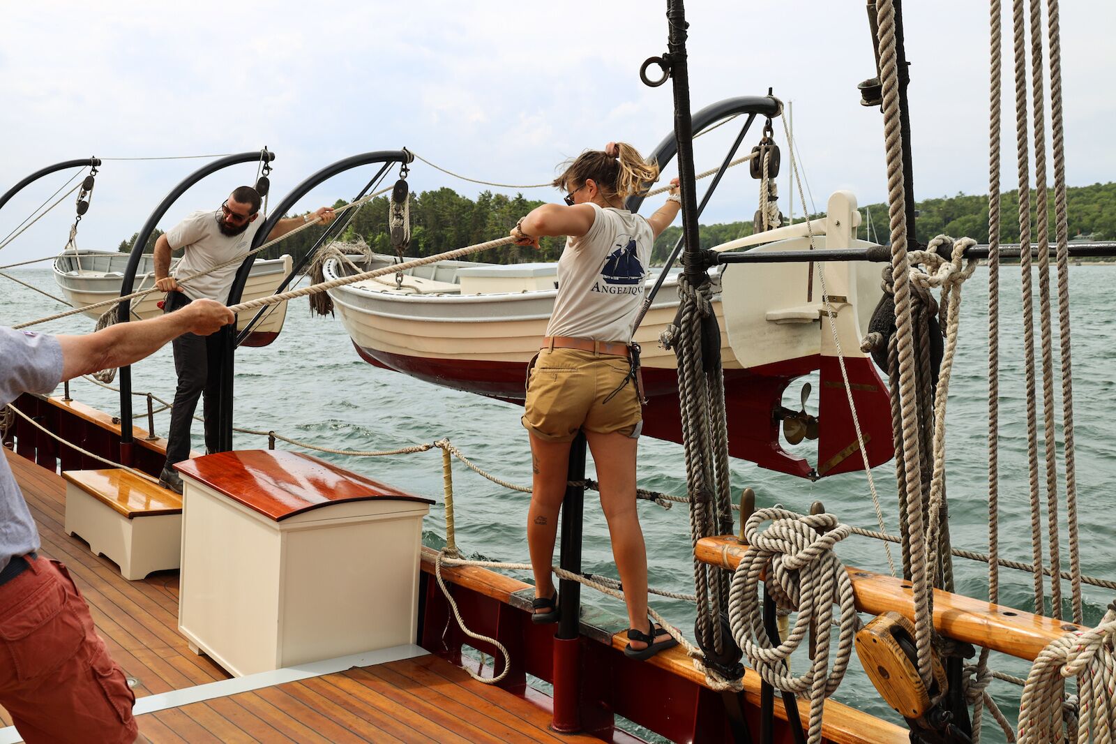 Crew members lower a boat in the water during a windjammer cruise in Maine