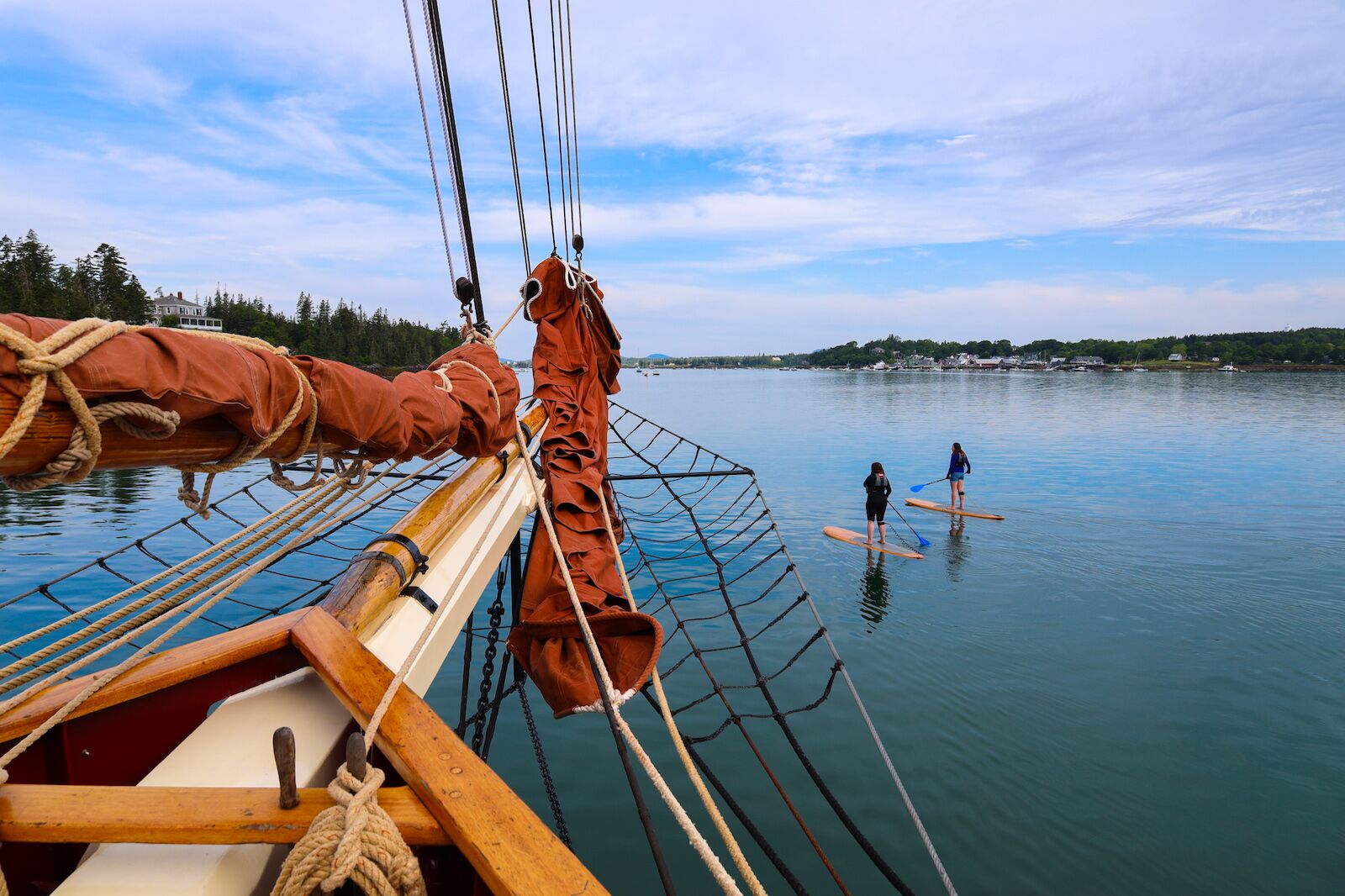 Two passengers aboard the Angelique for a windjammer cruise in Maine, take out paddle boards to explore the surroundings