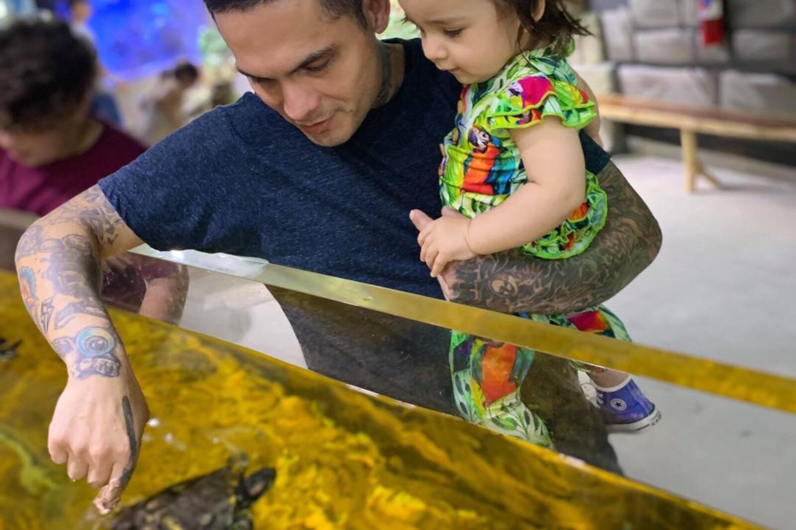 Man with child looking at turtle at Man with bird at Houston Interactive Aquarium 