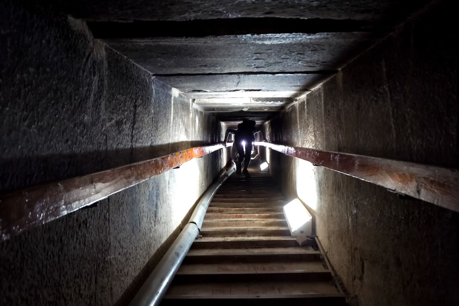 Person walking in a tunnel inside the Pyramid of Khufu; Some of the cavities in this pyramid remain a mystery.