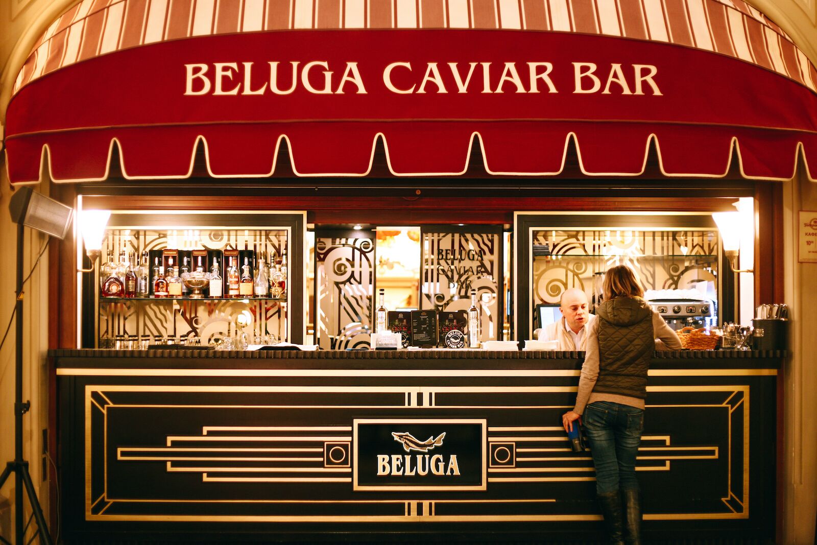 woman standing in front of beluga caviar bar with red awning in moscow