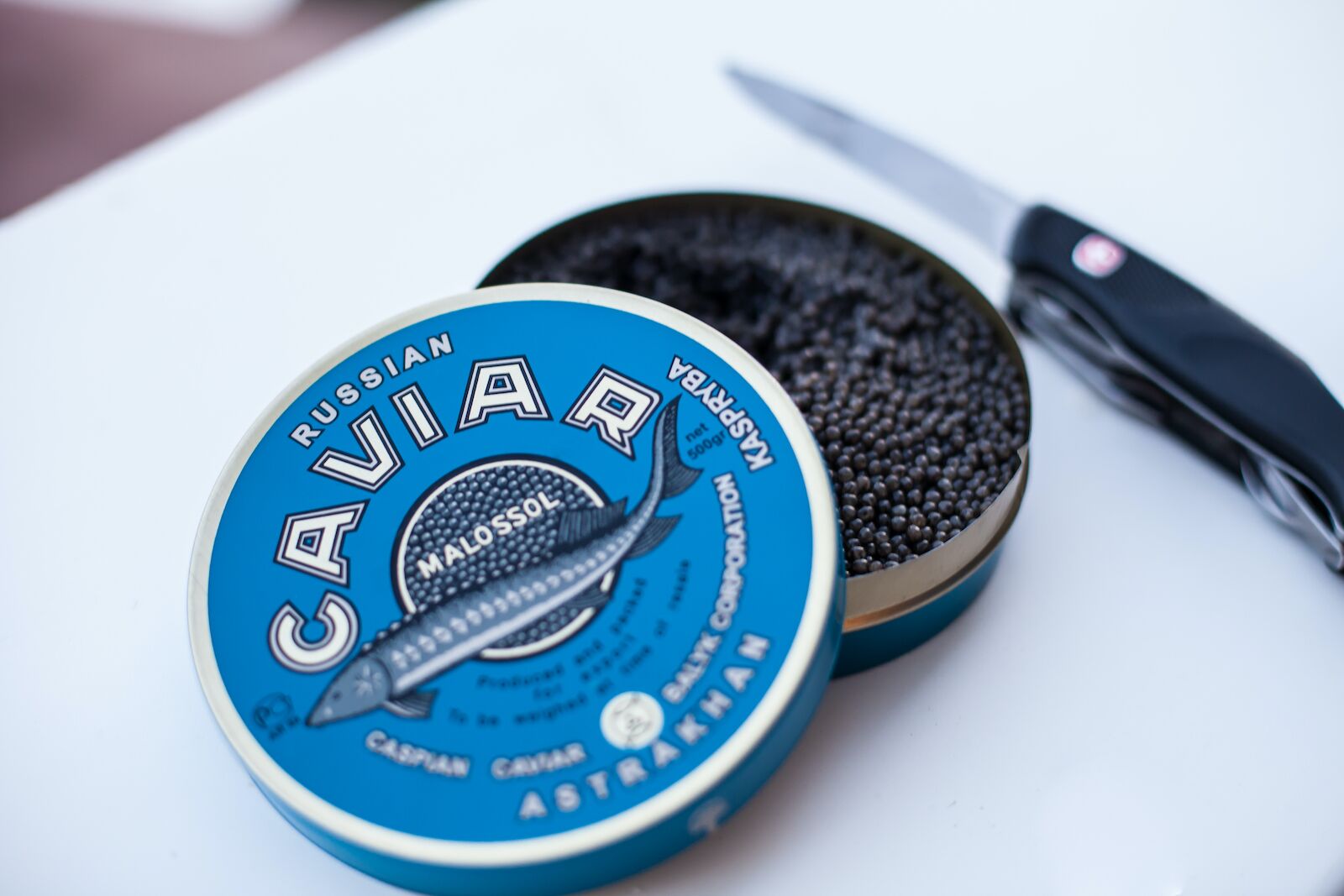 tin of beluga caviar with blue top and knife in the background