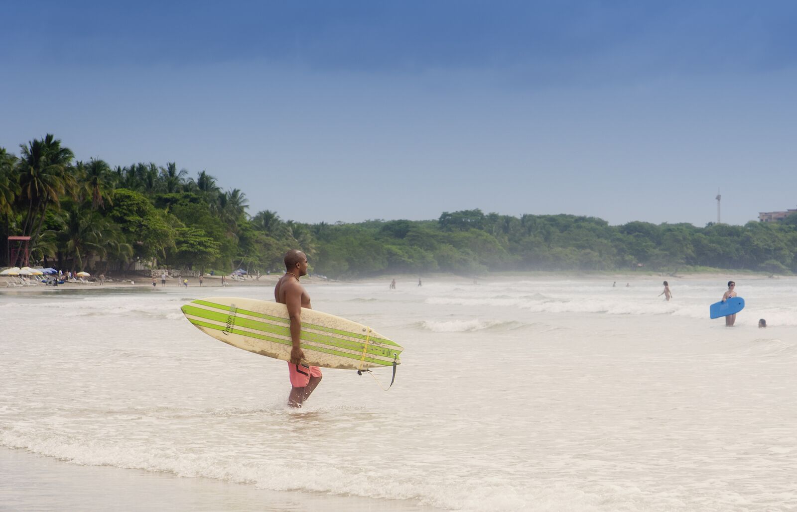 Man holding a surf board in Costa Rica. Read on to know more about the best time to visit Costa Rica and practise water sports like surfing and snorkeling