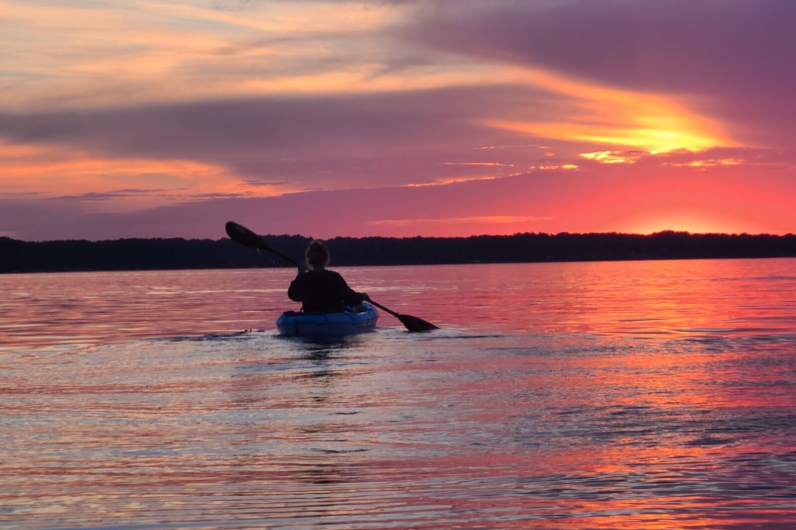 Person kayaking in Michigan at sunset