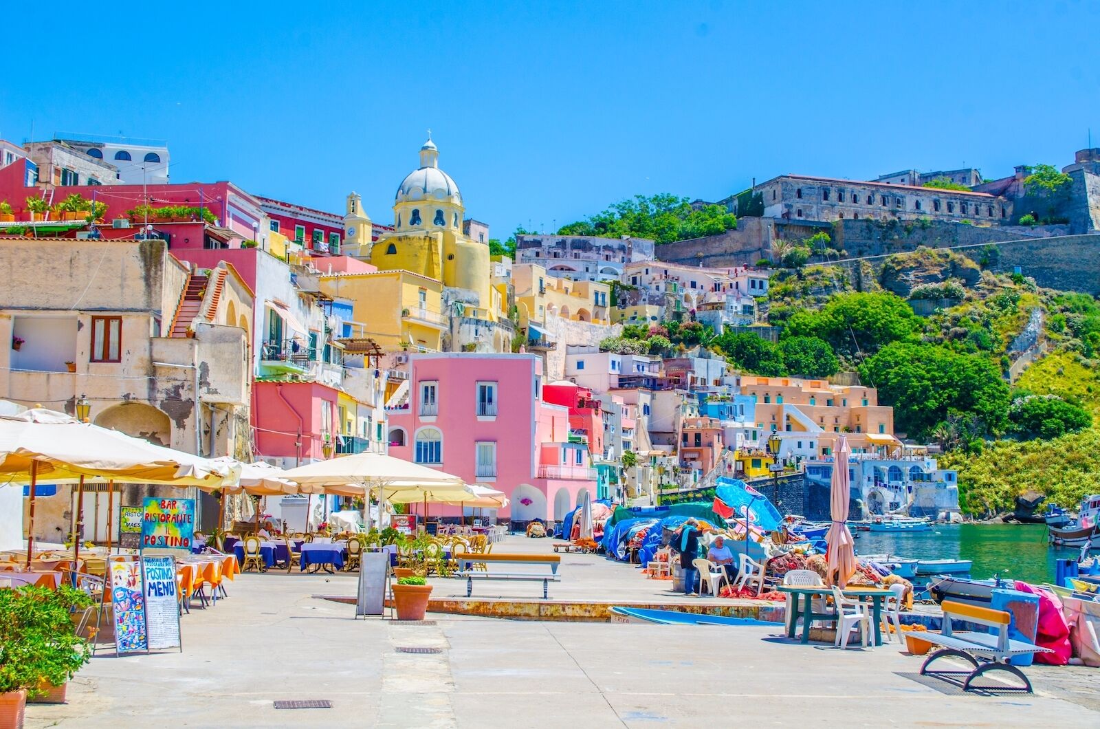 procida-italy-marina-and-sidewalk with restaurants and colorful buildings