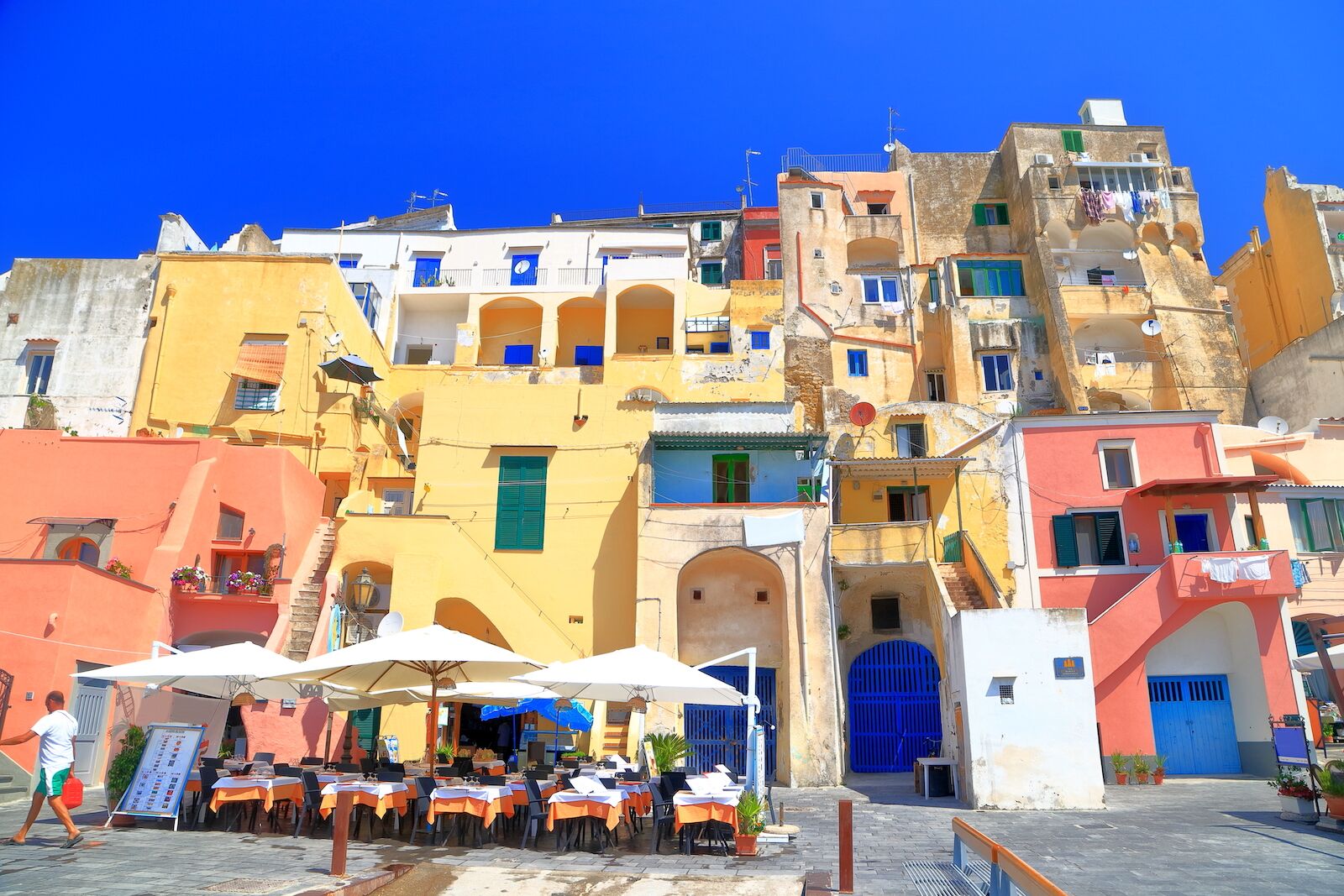 procida-italy-restaurant-with-view-of-marina and a man walking by