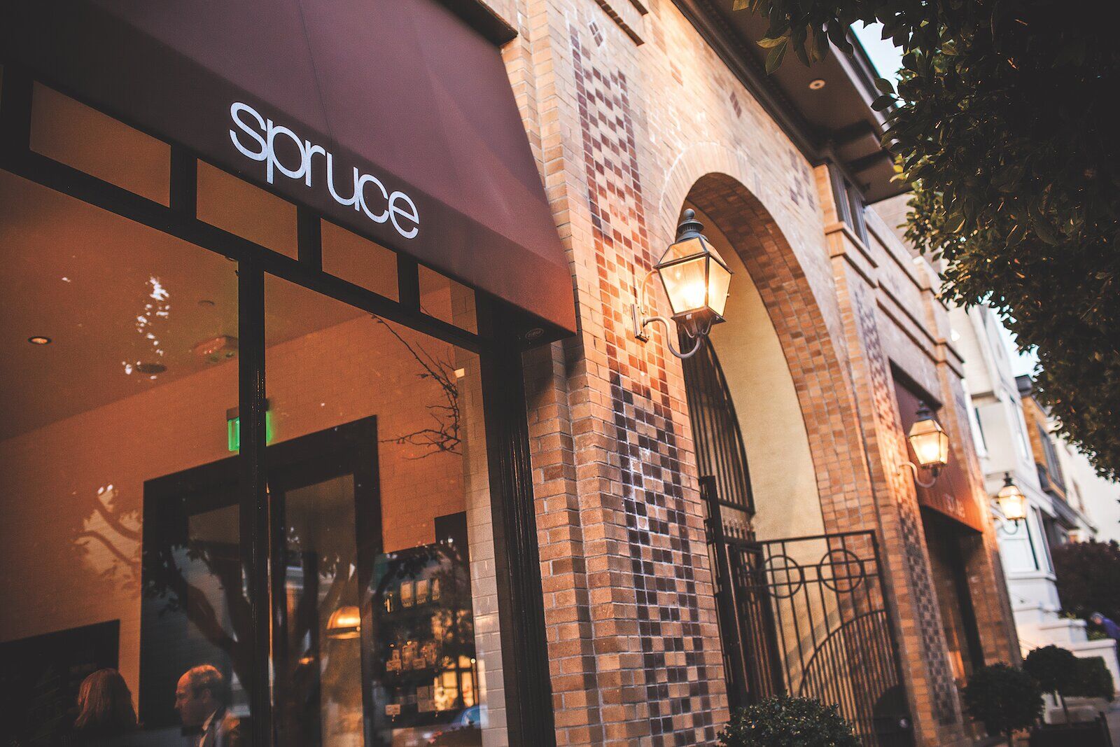 exterior of spruce restaurant with brown awning and brick facade