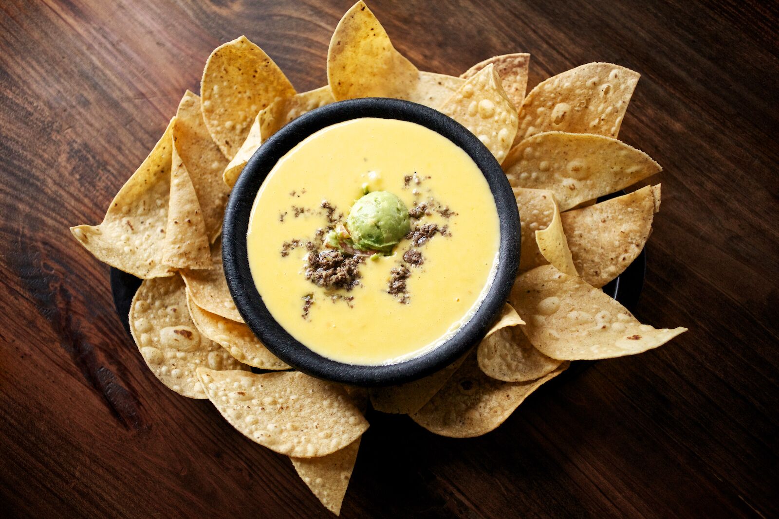 A bowl of queso with gaucamole surrounded by a basket of chips at Matt's El Rancho in Austin