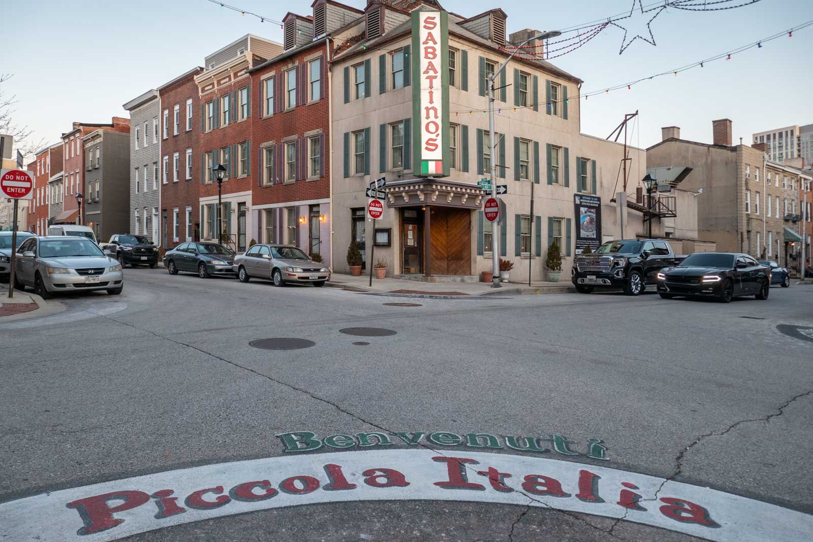 view of Sabatino's from the street with a mural painted in the street that says welcome to little italy