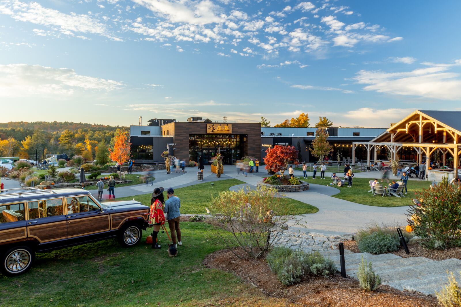 Exterior of Treehouse Brewery in Massachusets, with people sitting and standing on the lawn drinking beer