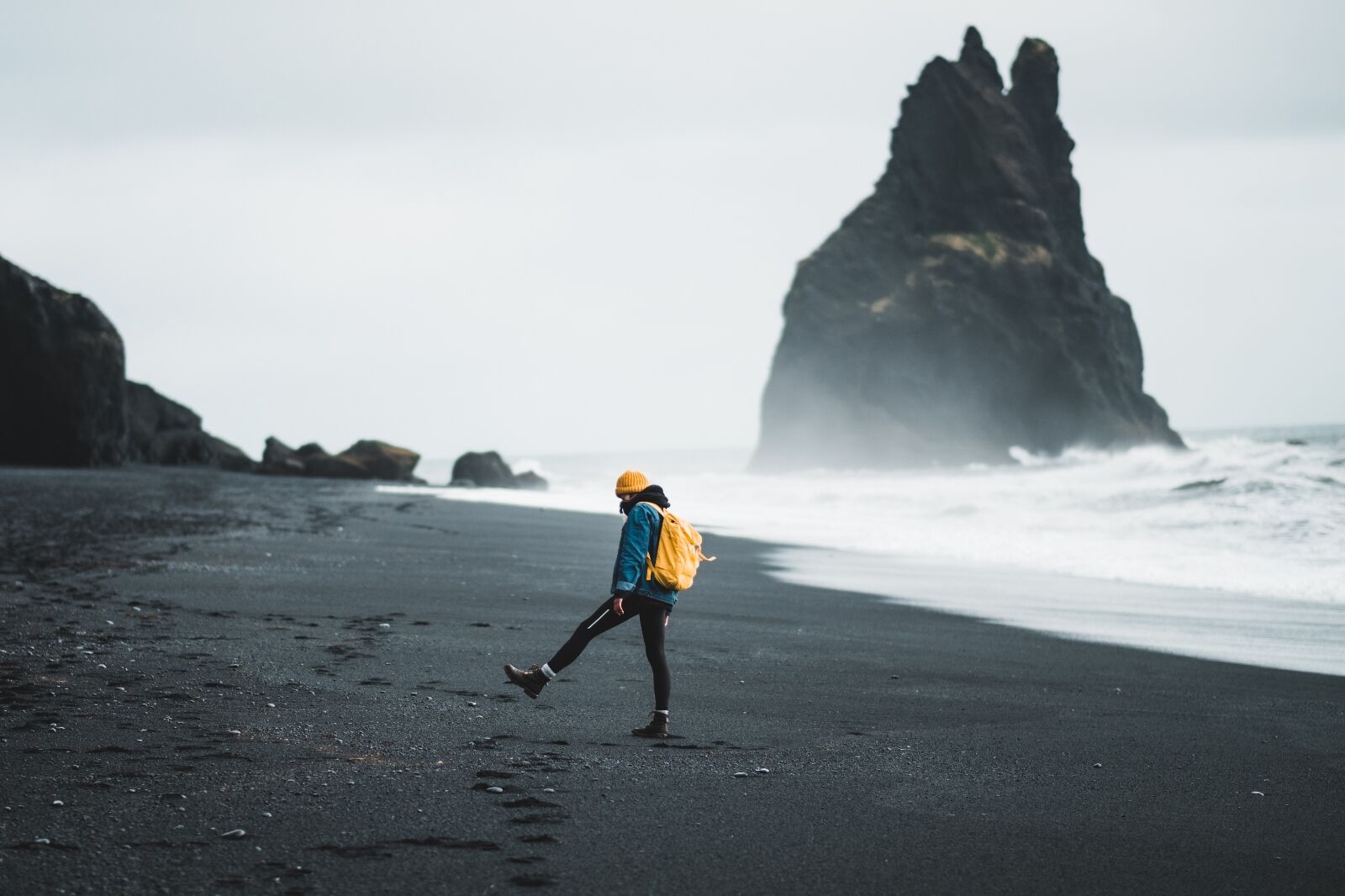 Traveler with backpack on black sand beach in Iceland 