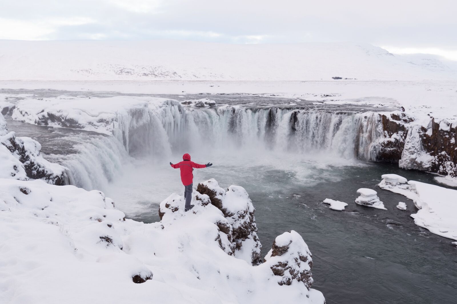Person standing over waterfall in winter in Iceland 