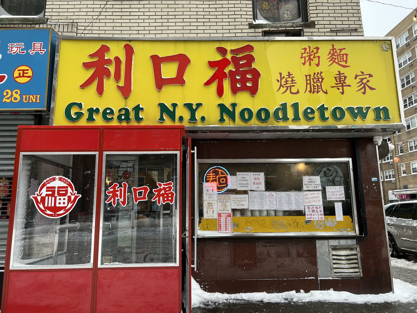 The exterior of Great NY Noodletown with red doors and a yellow sign