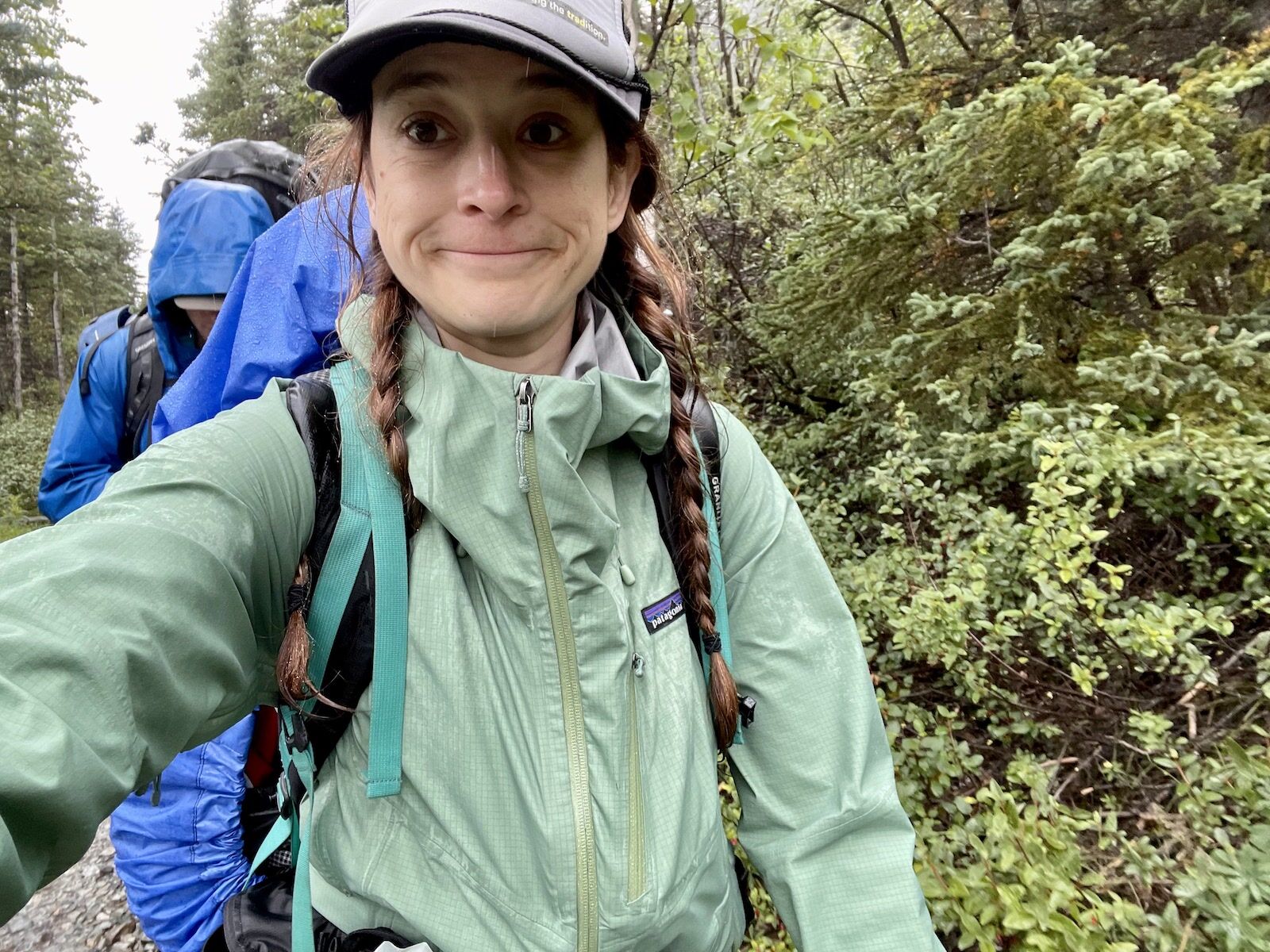 Backpacking woman wearing green Patagonia Granite crest rain jacket