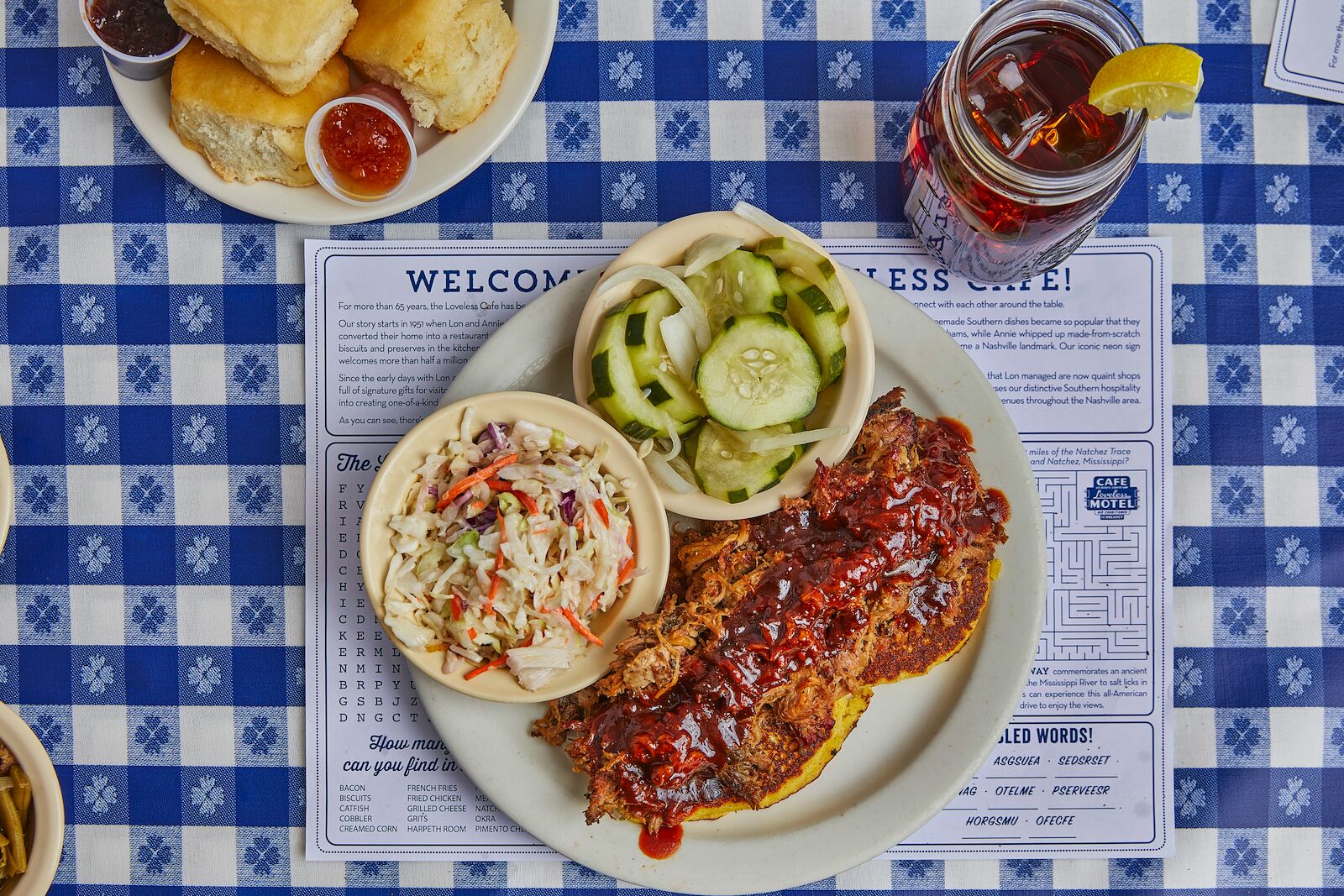 a platter of pulled pork, pickles, and coleslaw on a blue checked tablecloth at Loveless Cafe, where to go for the best bbq in Nashville