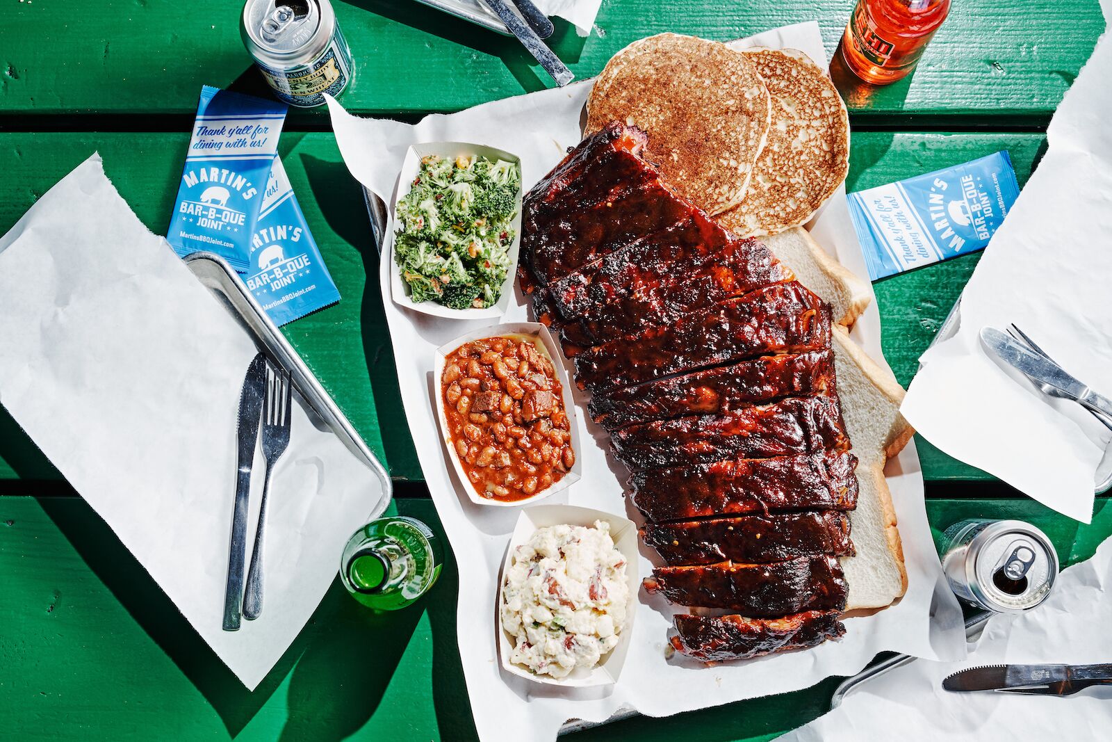 A platter of barbecue rubs with sides against a green background at Martin's Bar-B-Que Joint