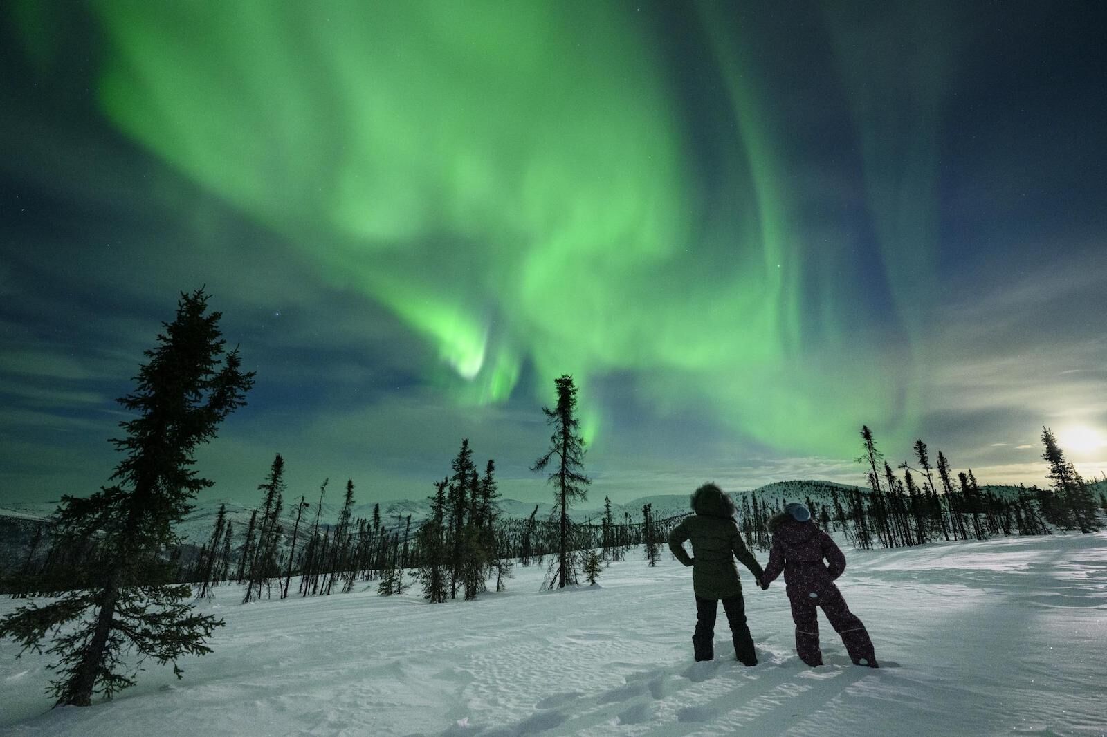 The best time to visit alaska for northern lights - two people looking at the aurora 