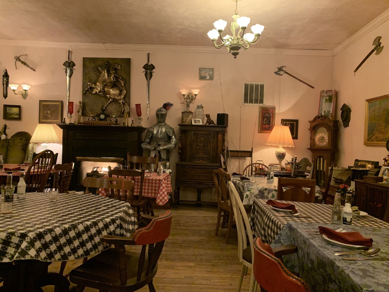 Interior of one of the best Italian restaurants in Pittsburgh, Zarra's, featuring a suit of armor, axes on the walls, and checked tablecothes