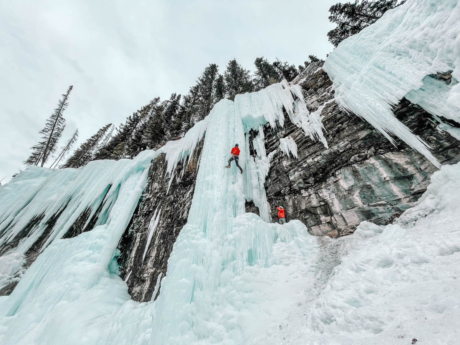 ice climbing on a banff weekend focused on wellness. Person in red jacket on ice column