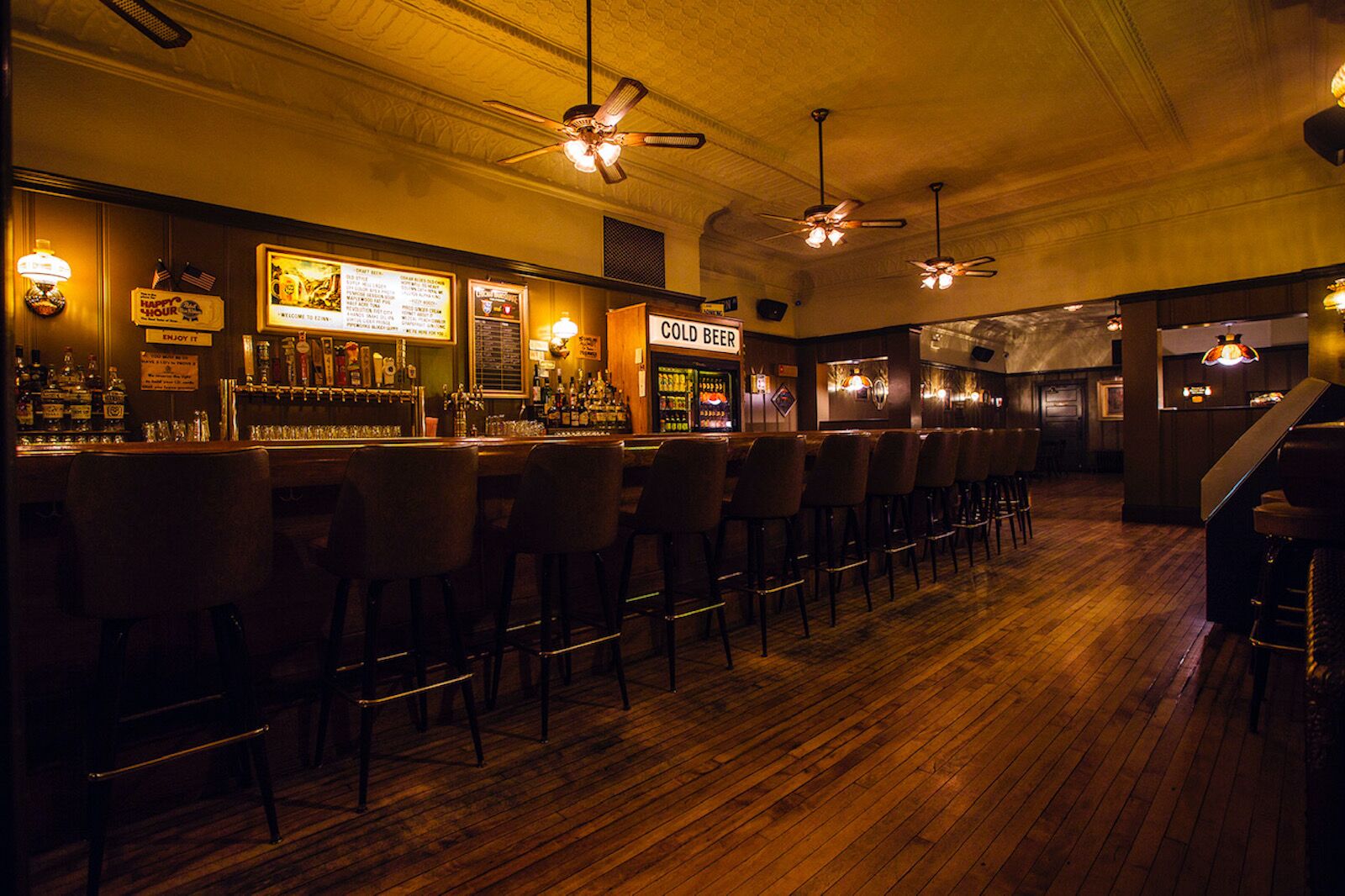Interior of EZ with cold beer cooler, row of taps at the bar, and wooden floors