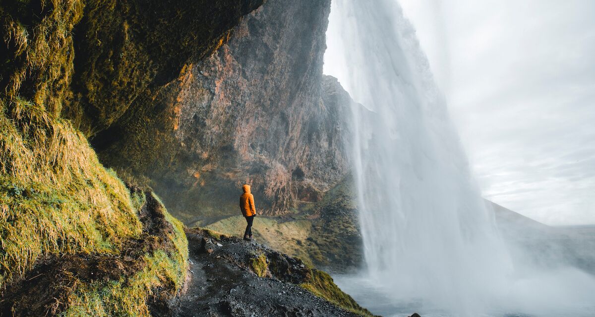 Person walking behind Seljalandsfoss waterfall in Iceland