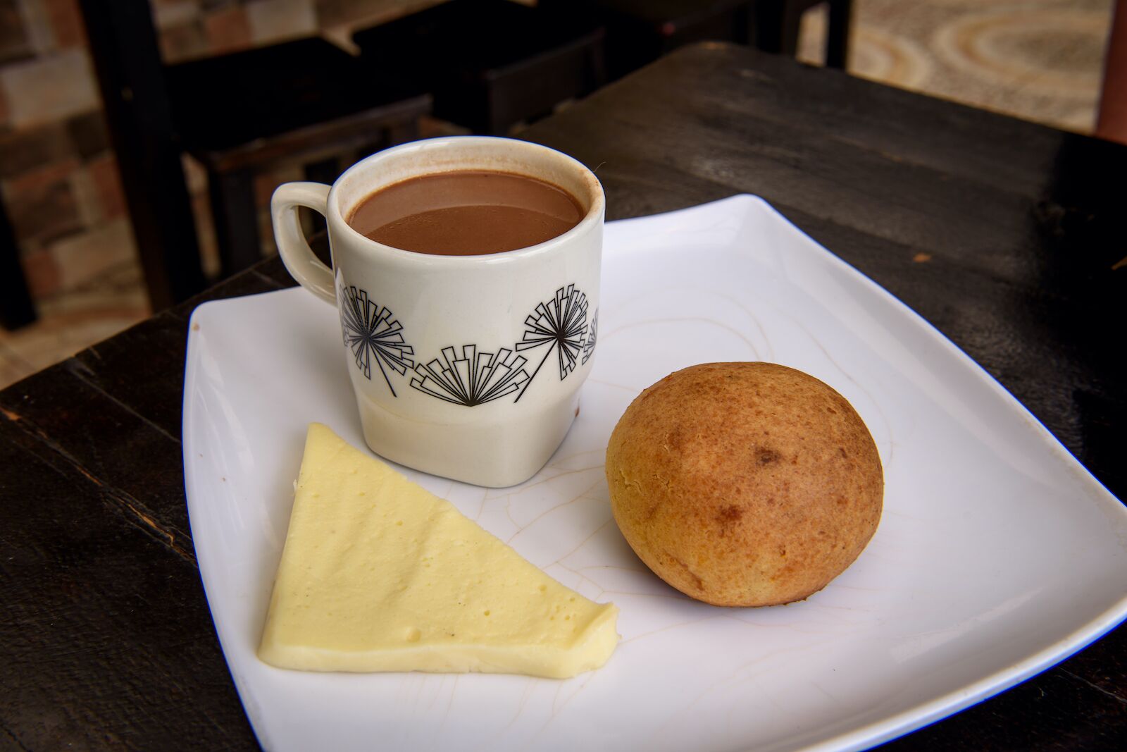 A type of Colombian breakfast food called almojabana, a bread roll served with a slice of cheese and a cup of hot chocolate