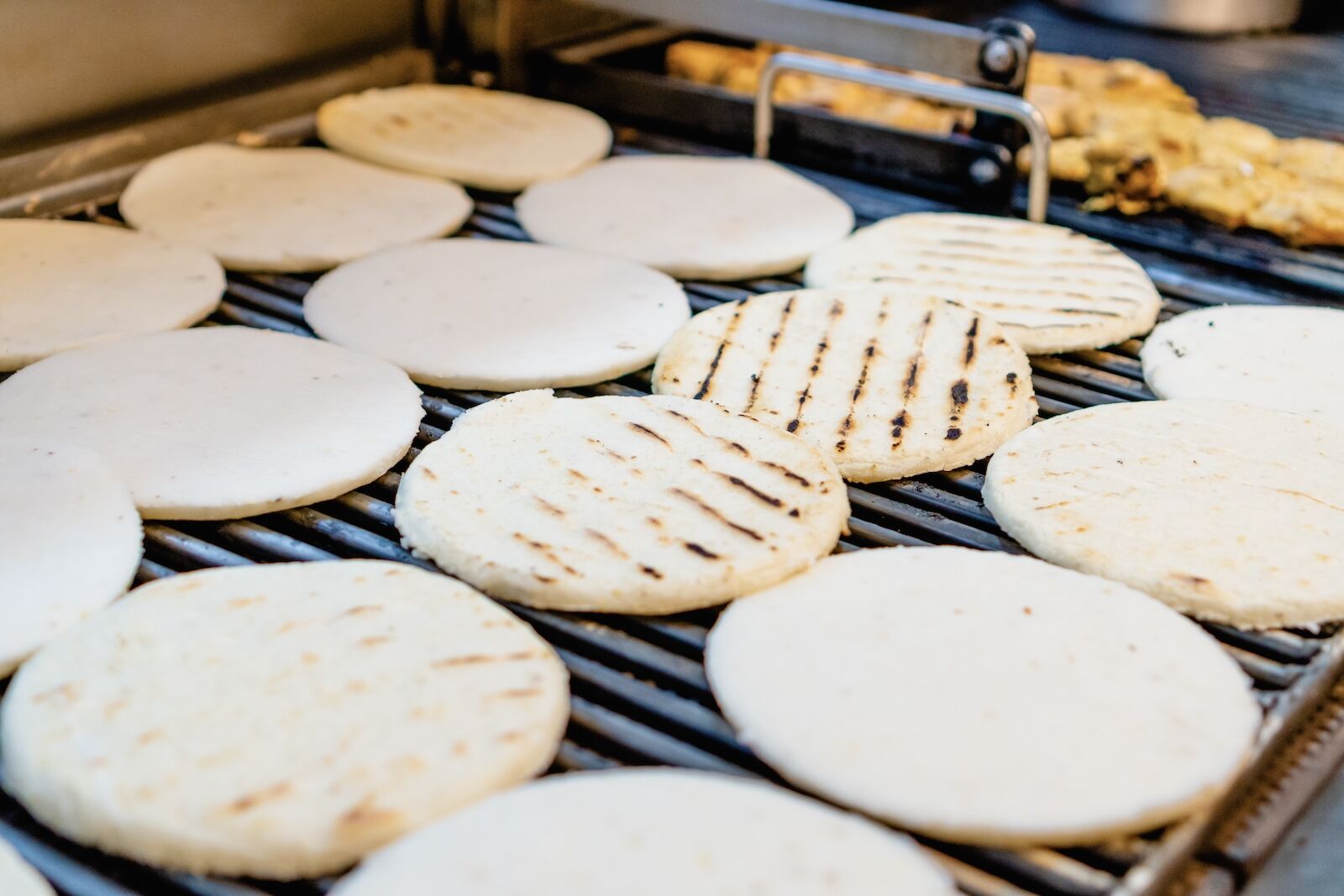 rows of arepas, a common Colombina breakfast food, on a grill