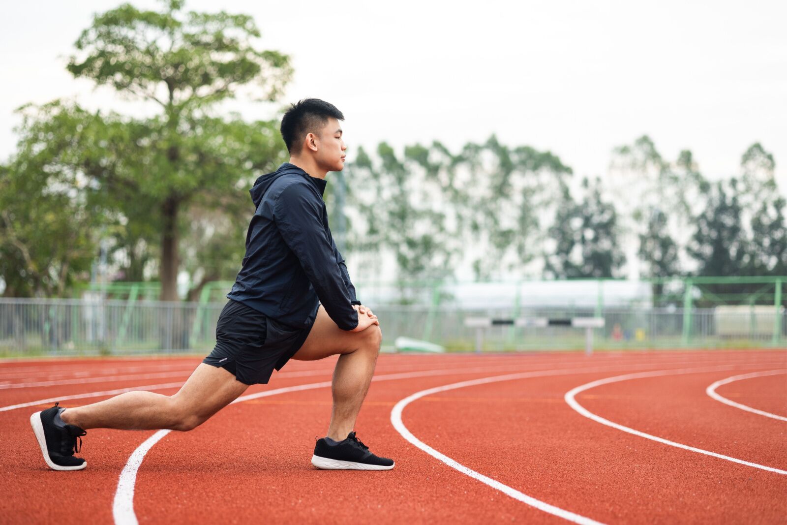 young guy stretching at a running track to train for a destination marathon