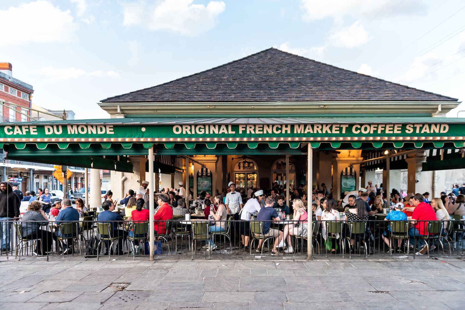 Cafe Du Monde with green and white awning and people sitting outside on the patio
