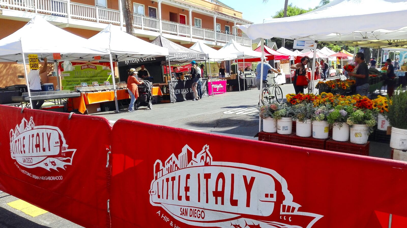 Little Italy farmer's market with vendors selling flowers and other goods