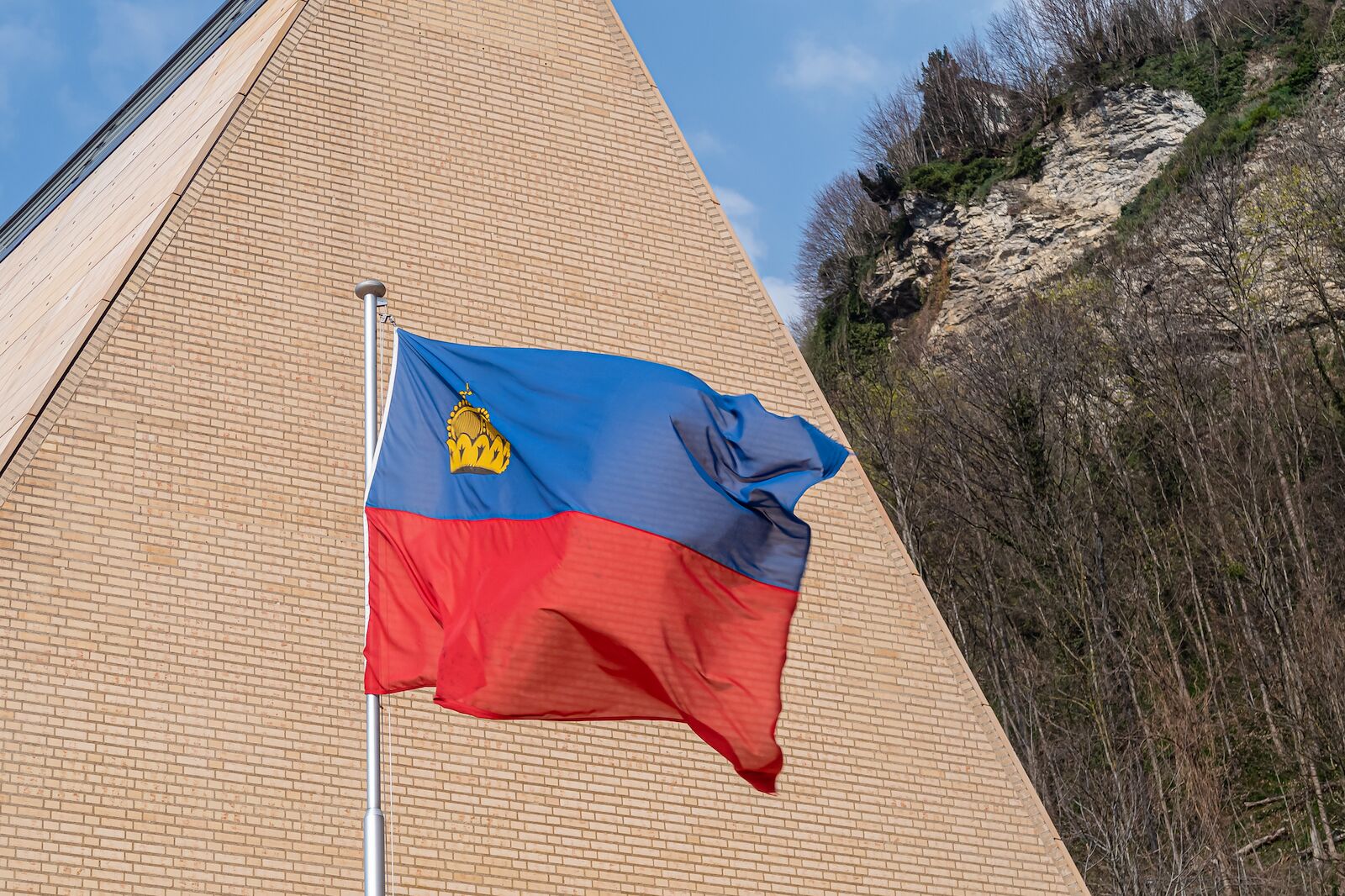 The national flag of the Principality of Liechtenstein in front of the Parliament building in Vaduz.