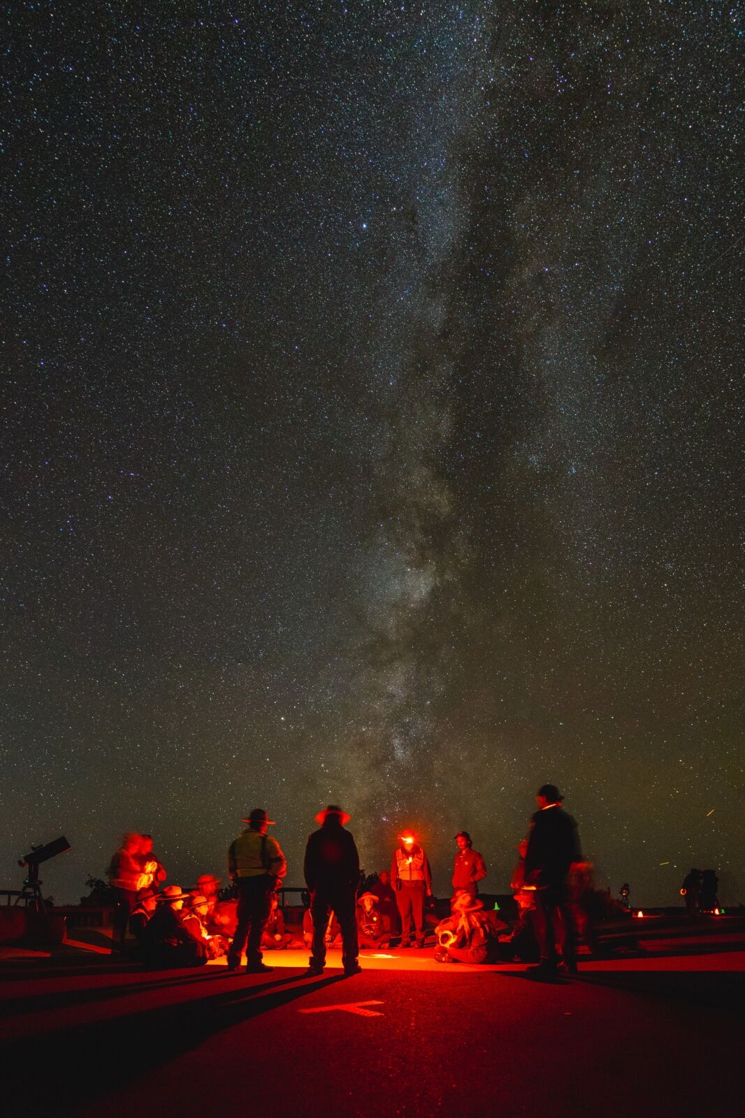 People gathered with red lights looking at stars in Arches National Park 