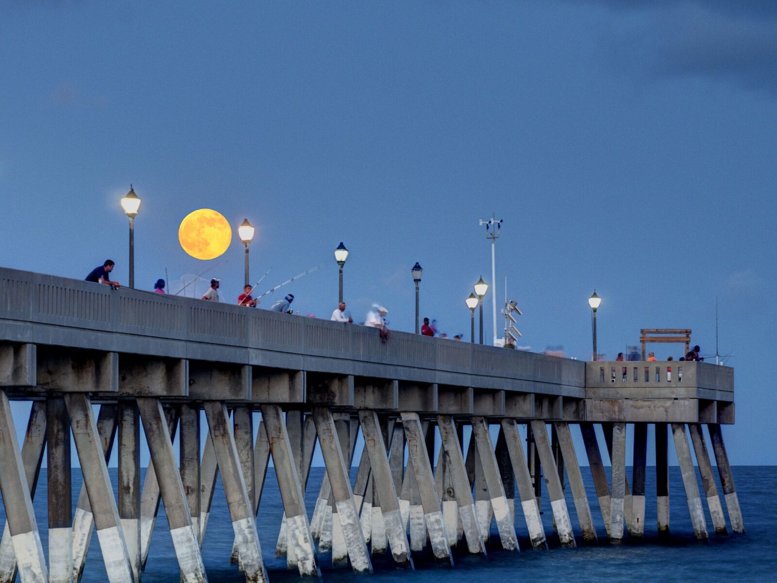 Red moon over pier at night 